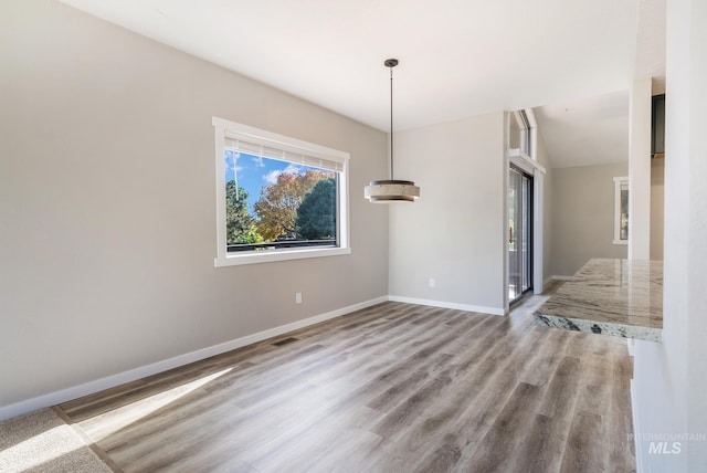 unfurnished dining area featuring light hardwood / wood-style flooring and lofted ceiling