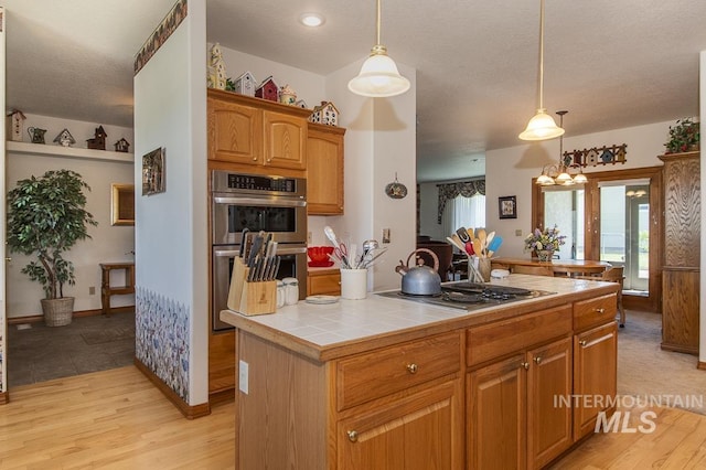 2555 E Quail Run Rd, Emmett, ID 83617 - kitchen featuring stainless steel appliances, tile counters, light wood-type flooring, pendant lighting, and a textured ceiling