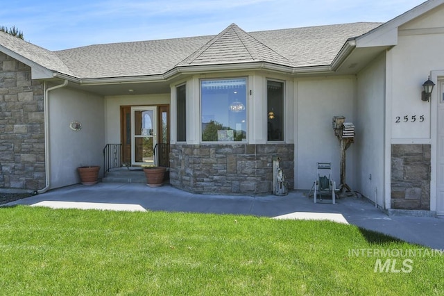 2555 E Quail Run Rd, Emmett, ID 83617 - view of exterior entry with stone siding, a yard, a shingled roof, and stucco siding