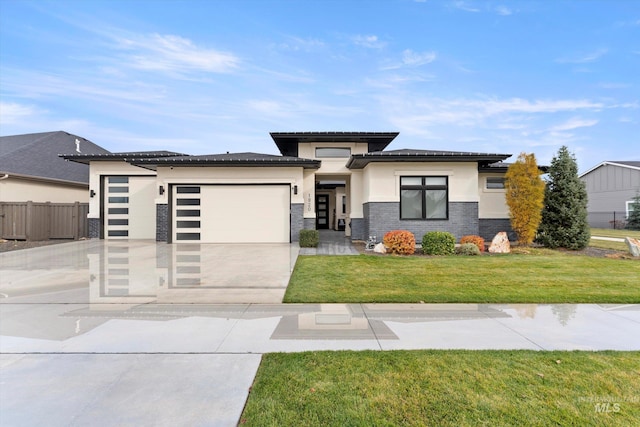 prairie-style house featuring concrete driveway, a front lawn, fence, a garage, and stucco siding