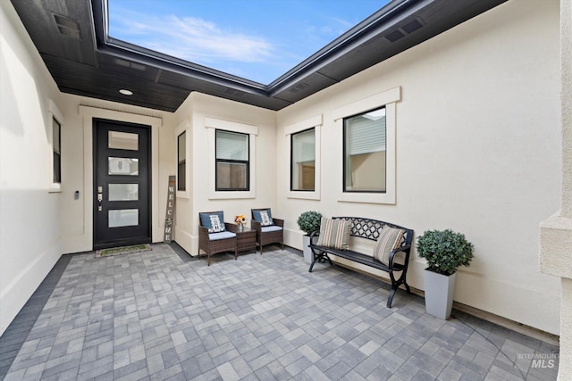 view of exterior entry with a patio and stucco siding