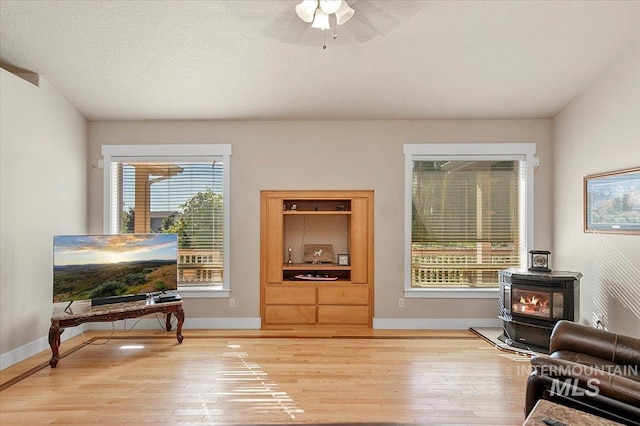 sitting room featuring a wood stove, light wood-style flooring, and baseboards