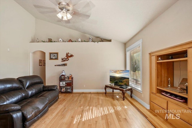 living area with arched walkways, light wood finished floors, lofted ceiling, ceiling fan, and baseboards