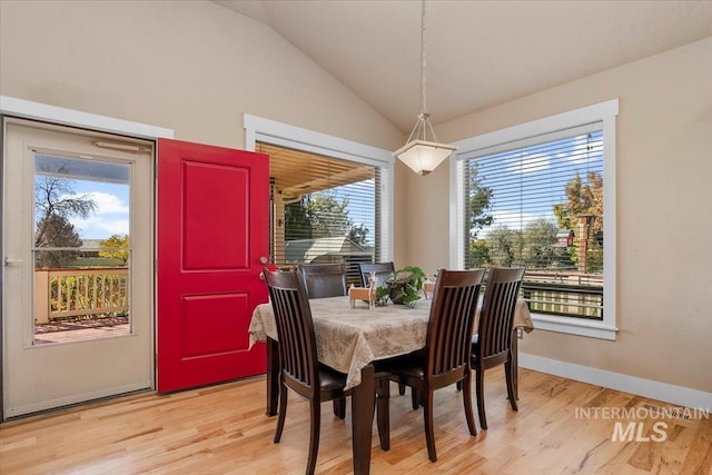 dining room with lofted ceiling, light wood-style flooring, and baseboards