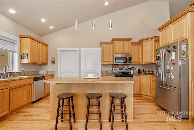 kitchen featuring a kitchen island, a breakfast bar, stainless steel appliances, light countertops, and a sink