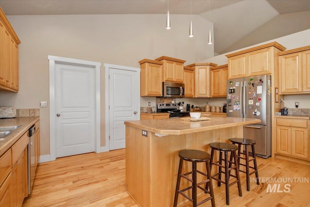 kitchen featuring stainless steel appliances, light countertops, light wood-style flooring, and a center island