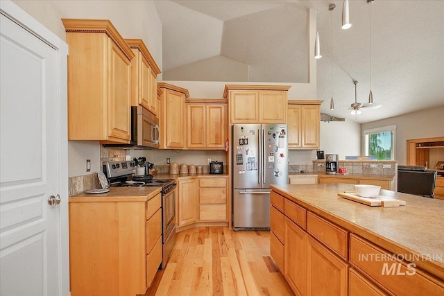 kitchen with light wood finished floors, stainless steel appliances, light countertops, light brown cabinets, and vaulted ceiling