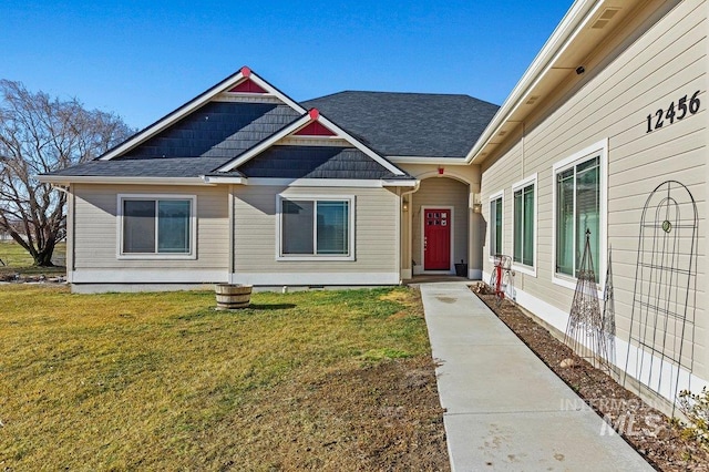 view of front of home featuring a shingled roof and a front lawn