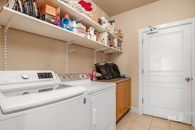 laundry area featuring washer and dryer, cabinet space, and light tile patterned floors