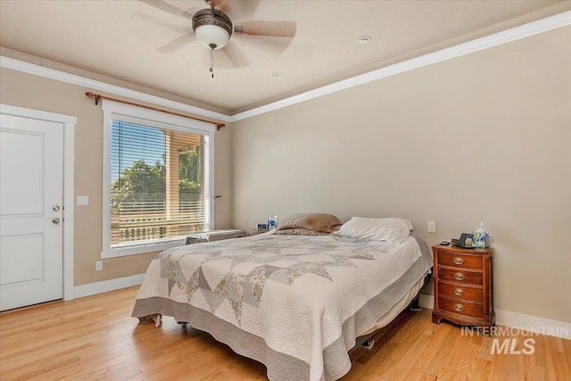 bedroom with a ceiling fan, crown molding, baseboards, and wood finished floors