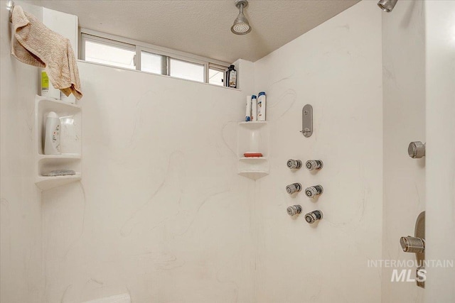 room details featuring a shower and a textured ceiling