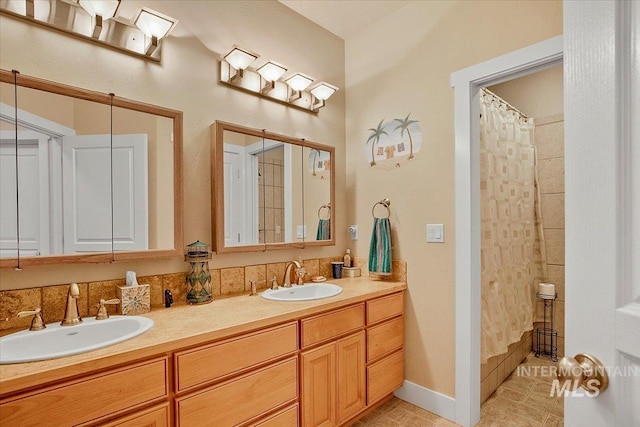 full bath featuring double vanity, curtained shower, a sink, and baseboards