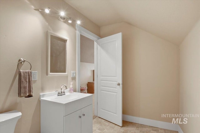 bathroom featuring toilet, baseboards, lofted ceiling, and vanity