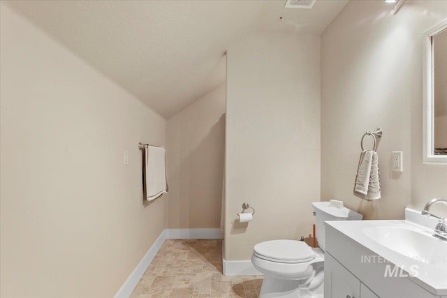 half bath featuring visible vents, toilet, vaulted ceiling, vanity, and baseboards