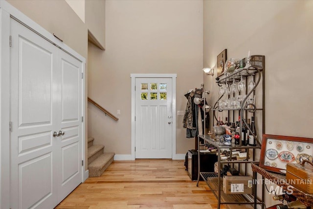 foyer featuring stairs, a high ceiling, light wood-type flooring, and baseboards