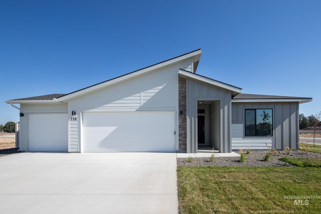 view of front of house with a garage, a front yard, board and batten siding, and concrete driveway