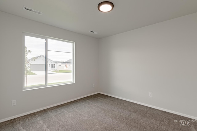 unfurnished room featuring baseboards, visible vents, and carpet flooring