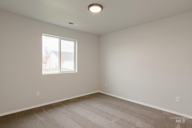 empty room featuring carpet floors, visible vents, and baseboards