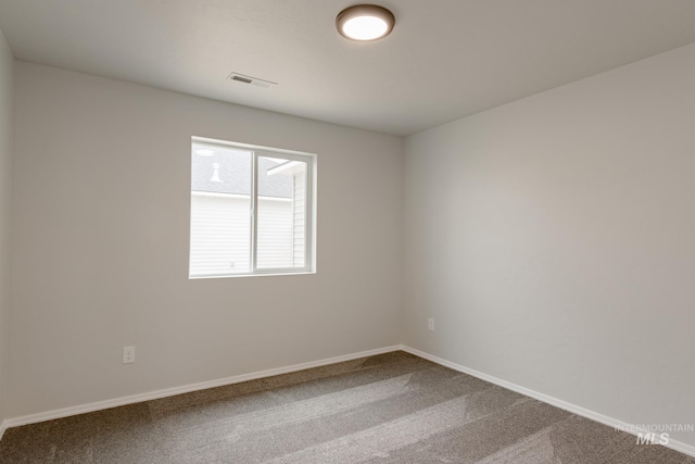 carpeted spare room with visible vents and baseboards