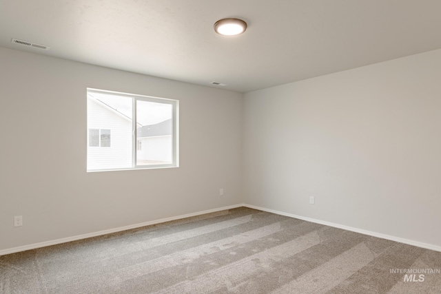 carpeted spare room with visible vents and baseboards