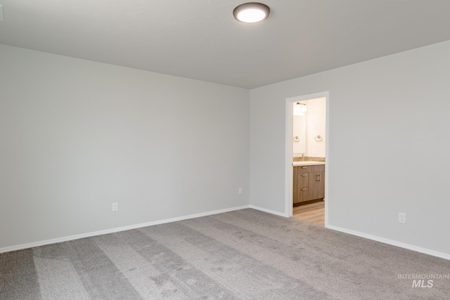 unfurnished bedroom with baseboards, connected bathroom, and light colored carpet