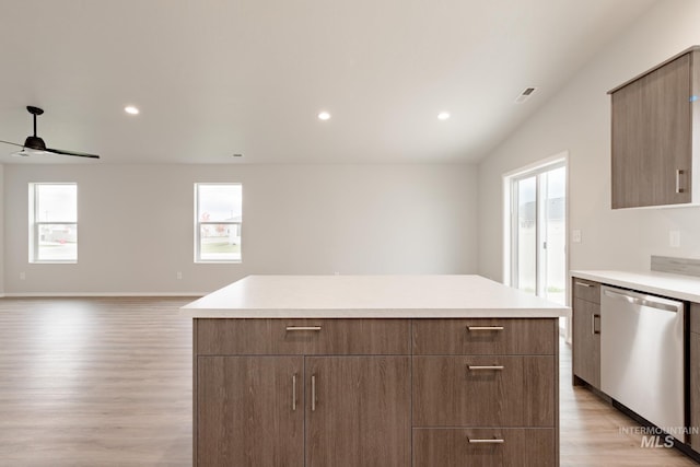 kitchen with a wealth of natural light, light countertops, stainless steel dishwasher, and a center island