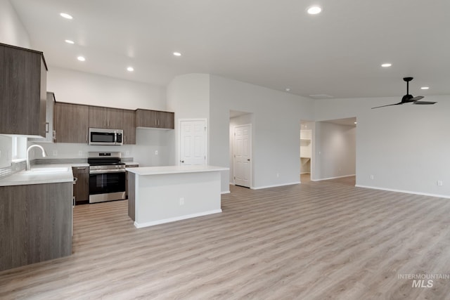 kitchen featuring a kitchen island, a ceiling fan, open floor plan, light countertops, and appliances with stainless steel finishes