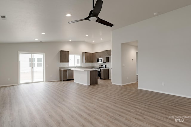 kitchen with stainless steel appliances, light countertops, open floor plan, a kitchen island, and modern cabinets