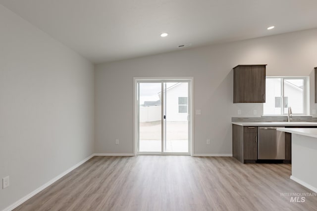 kitchen with a sink, a wealth of natural light, light countertops, and stainless steel dishwasher