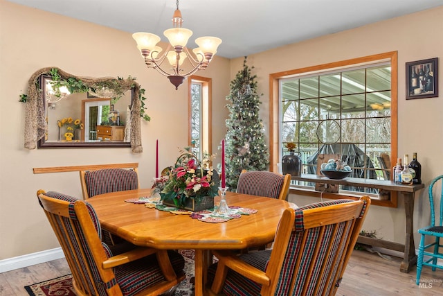 dining area with light hardwood / wood-style floors and an inviting chandelier