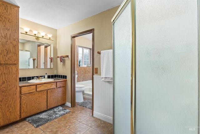 bathroom with tile patterned flooring, vanity, toilet, and walk in shower