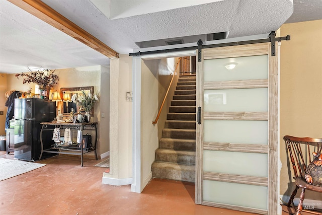 stairs featuring a barn door, concrete flooring, and a textured ceiling