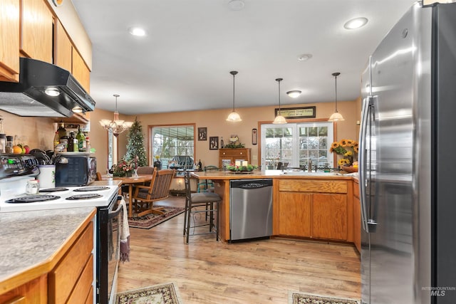 kitchen featuring ventilation hood, stainless steel appliances, hanging light fixtures, and a chandelier