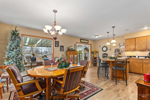 dining area with light hardwood / wood-style floors and a notable chandelier