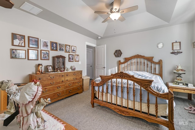 carpeted bedroom with ceiling fan, lofted ceiling, and a tray ceiling