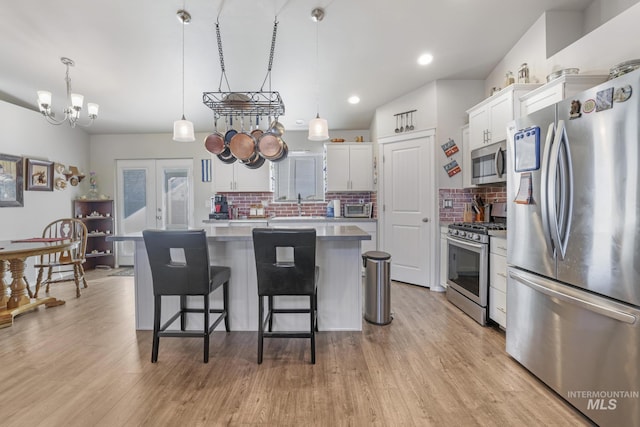 kitchen featuring french doors, a center island, appliances with stainless steel finishes, pendant lighting, and white cabinets