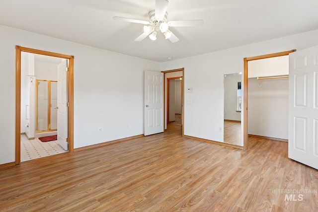 unfurnished bedroom with ceiling fan, connected bathroom, light wood-type flooring, a closet, and a walk in closet