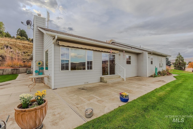 back of house with a patio and a lawn