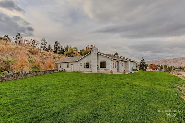 exterior space with a yard, a mountain view, and a patio