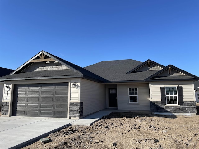 view of front of house with stone siding, driveway, and an attached garage