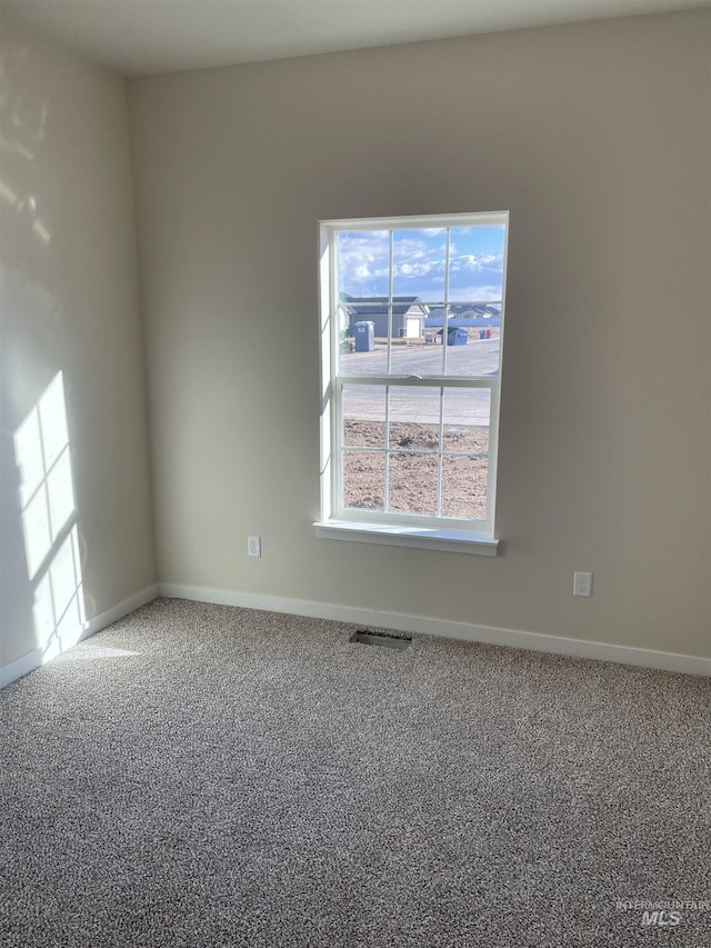 carpeted spare room featuring baseboards and visible vents