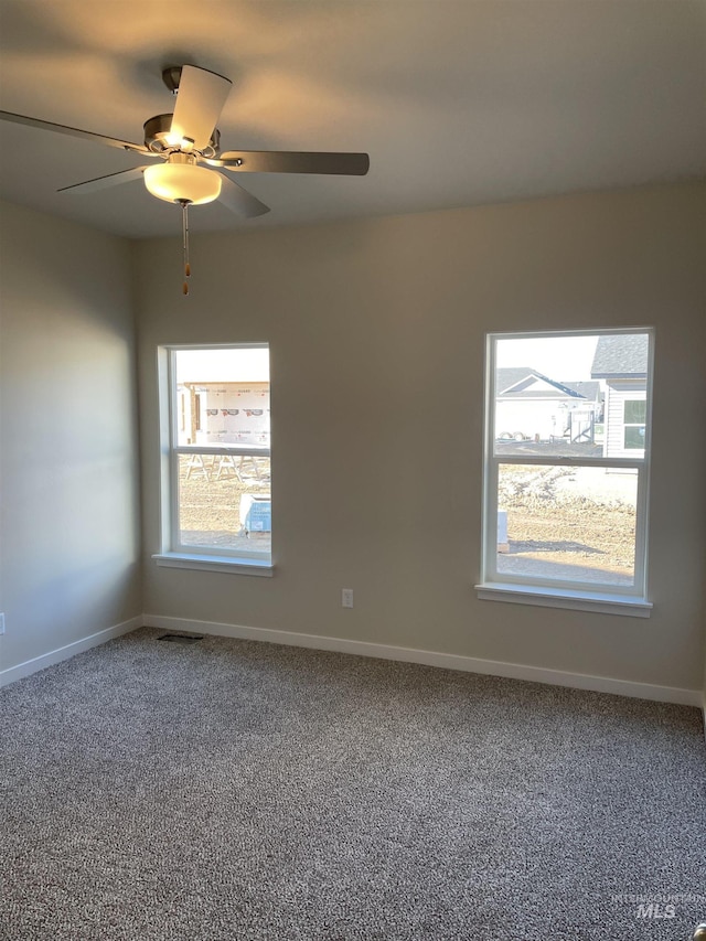 empty room with carpet flooring, visible vents, and baseboards