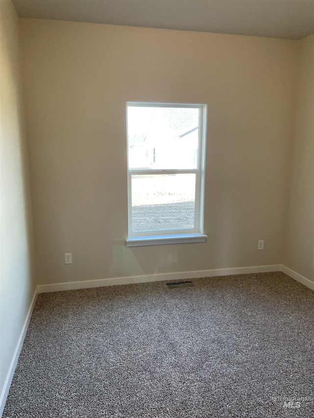 unfurnished room featuring carpet flooring, visible vents, and baseboards