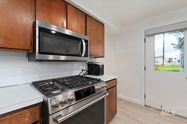5009 Airport Rd, Nampa, ID 83687 - kitchen featuring stainless steel appliances, light countertops, light wood finished floors, brown cabinets, and baseboards