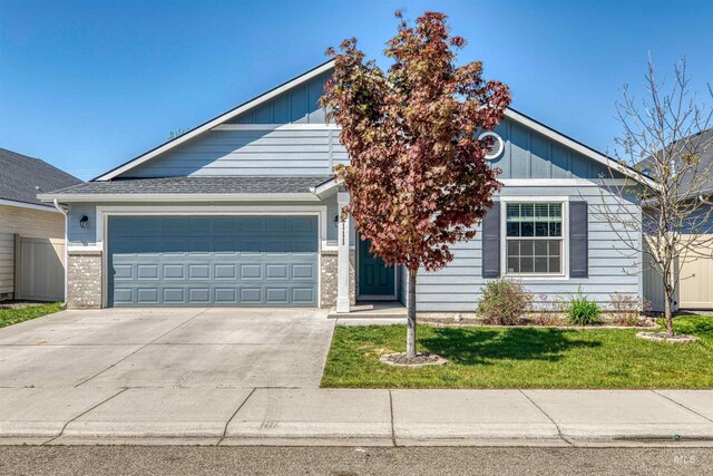 view of front of property with an attached garage, a front lawn, board and batten siding, and driveway