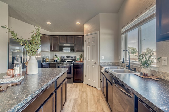 kitchen featuring a sink, dark countertops, light wood-style floors, and stainless steel appliances