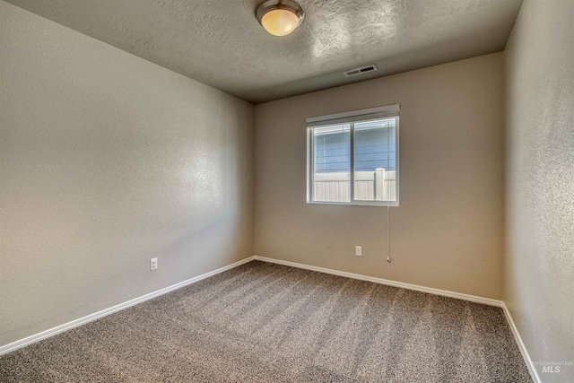 carpeted empty room featuring baseboards, a textured wall, a textured ceiling, and visible vents