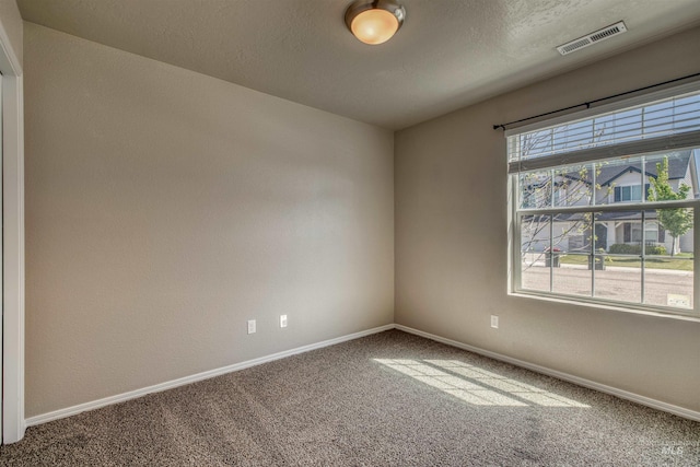 empty room with visible vents, a textured wall, baseboards, a textured ceiling, and carpet flooring