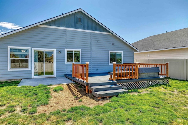 back of house with a yard, a deck, fence, and board and batten siding
