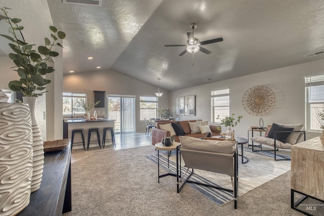 living room with a textured ceiling, a ceiling fan, lofted ceiling, and visible vents